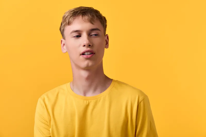 Young man in a bright yellow shirt stands before a vivid yellow backdrop, delivering bold color, casual fashion, and studio lifestyle aesthetics for modern advertising, branding, and social campaigns