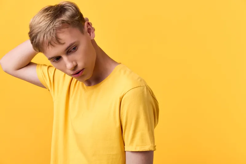 Man in a yellow t shirt on a yellow backdrop, thoughtful pose, casual style, studio lighting, and subtle mood ideal for lifestyle, fashion, or product marketing concepts