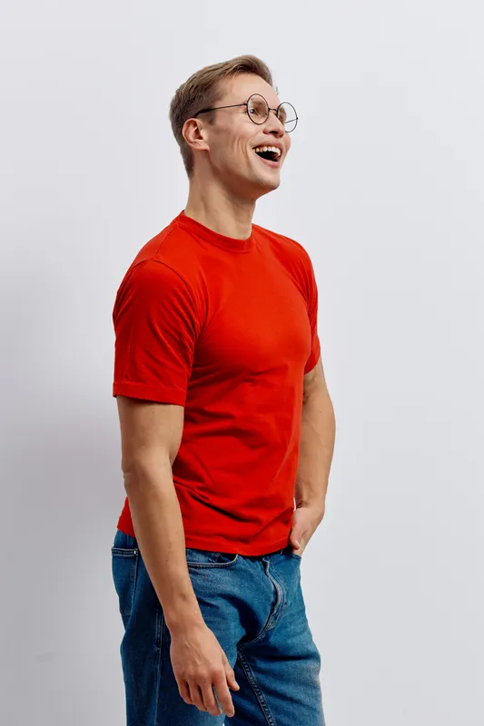 laughing man wearing red t-shirt and glasses standing isolated on white background casual look cheerful emotion digital detox mental health concept