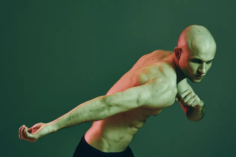 Athletic man in dynamic pose showcasing strength and determination, with focus on movement and energy. Background features a cool-toned color palette.