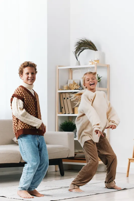Authentic scene of playful children in a cozy living space, capturing school age charm, genuine movement, and spontaneous joy during a lighthearted moment at home.