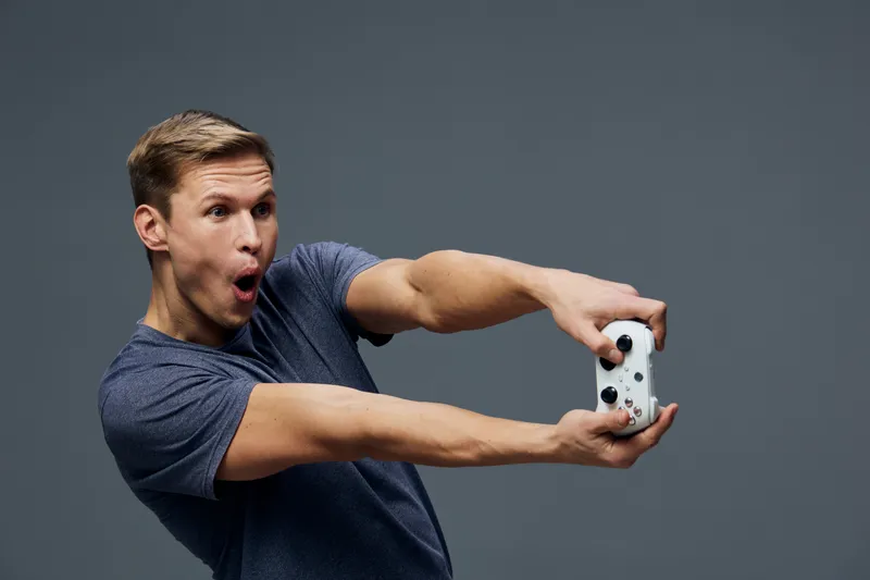 Casual young man with short hair wearing navy t-shirt making funny face while taking selfie with smartphone isolated on grey background. Lifestyle, technology, entertainment, happiness, casual, portra