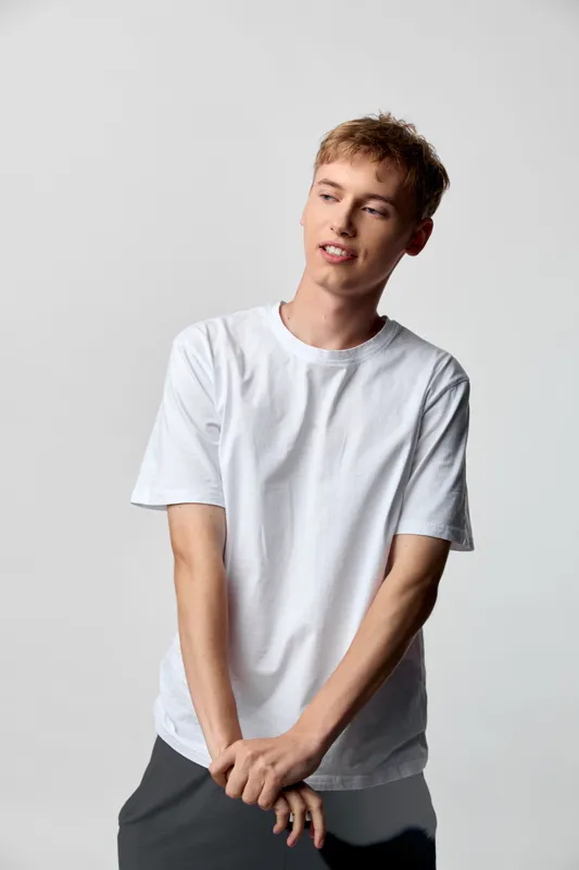 Casual man wearing a white t shirt modeling in studio with a relaxed pose, clean background, and contemporary fashion vibe suitable for lifestyle and apparel use