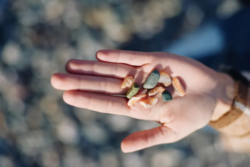 Hand holding colorful stones and pebbles in palm, outdoor nature setting, closeup detail and textured surface, calm and natural mood for outdoor life and collection themes