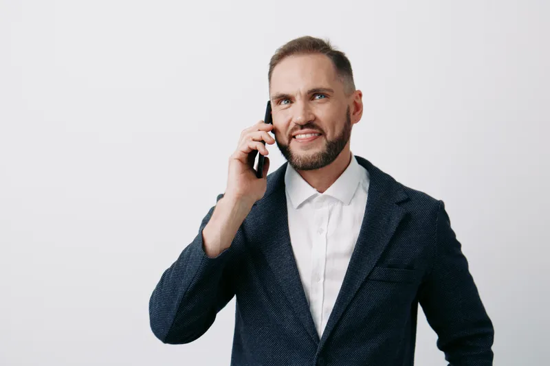 A confident business professional man talks on a smartphone against an isolated colored background, conveying calm focus, determination, and approachable leadership.