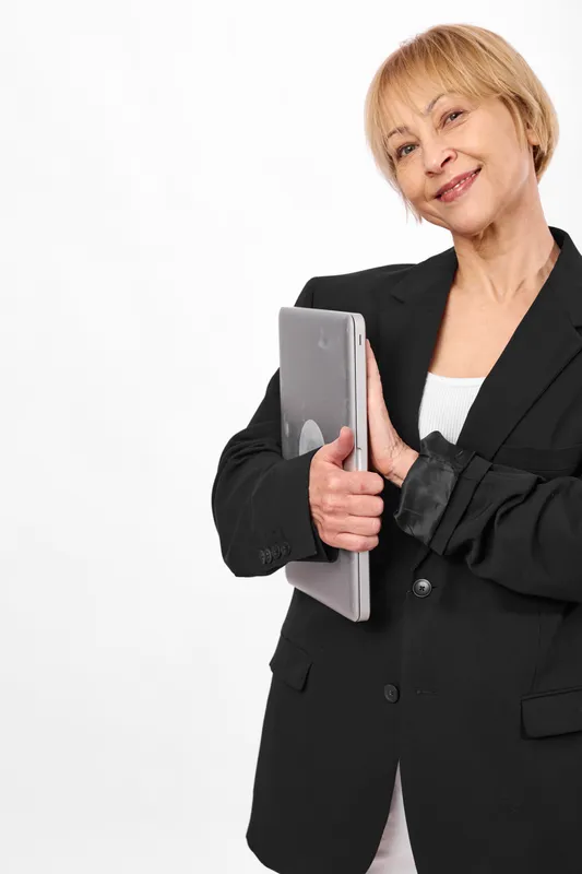 Confident older businesswoman in black suit smiling while holding a gray folder on a clean white background, portrait concept for office professionalism and career