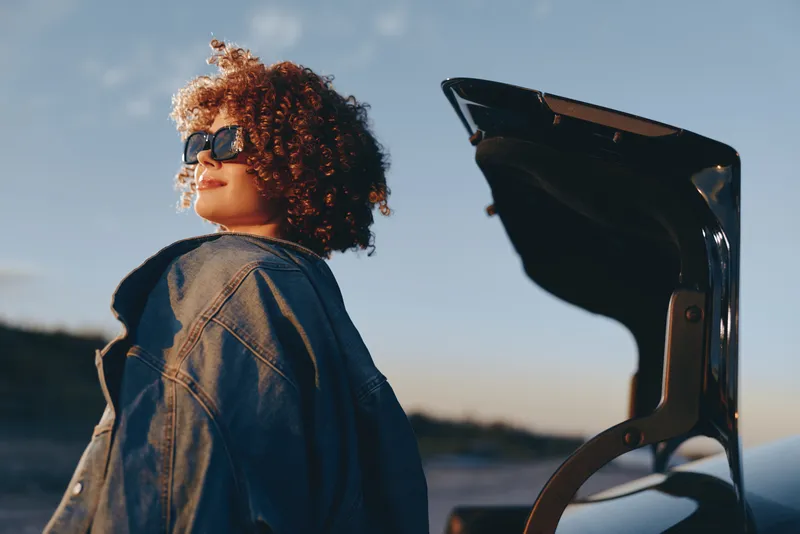 Woman lifestyle graduate graduation cap sunglasses curly denim outdoors sky, outdoor sunset portrait of a woman in denim jacket with curly hair and dark sunglasses holding an academic cap, education