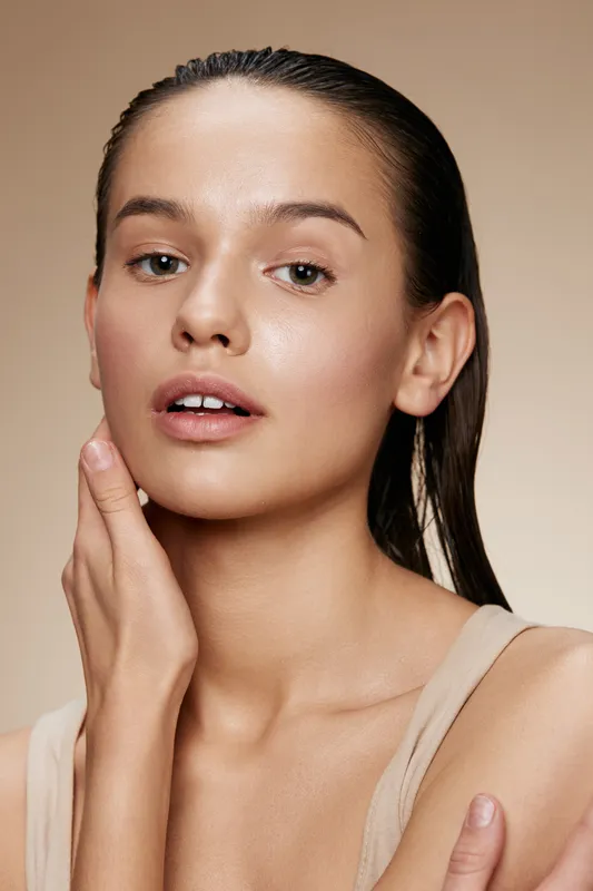 Natural beauty portrait of a young woman with wet hair, showcasing glowing skin and a light makeup look, ideal for skincare and beauty concept promotion