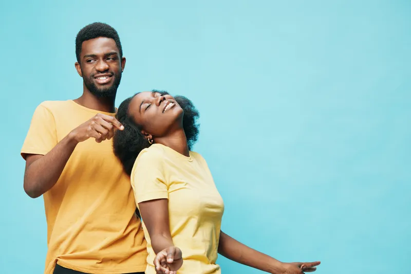 Joyful young couple enjoying their time together, wearing matching yellow t shirts, set against a bright blue background, exuding love and happiness