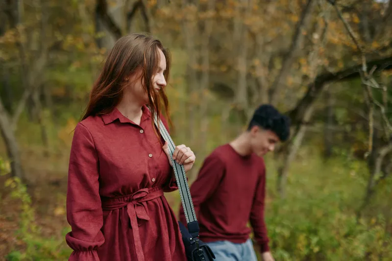 Candid portrait of a young couple walking through an autumn woodland, captured with natural light to convey authenticity and emotional credibility in a quiet, honest moment.