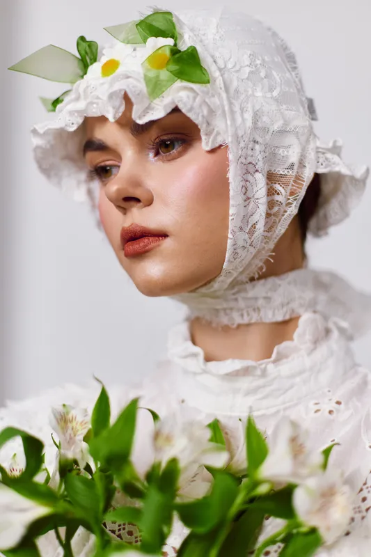 Portrait of a model in a lace bonnet and floral dress, conveying a serene emotion with a soft color palette, ideal for spring themed fashion