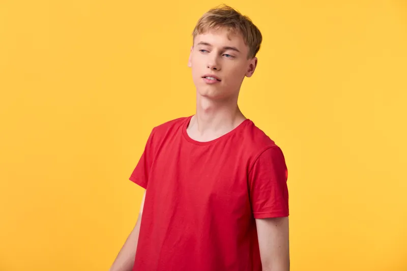 Man, young, red shirt in a casual studio with a bright yellow background, relaxed pose and confident expression, fashion image for lifestyle and branding