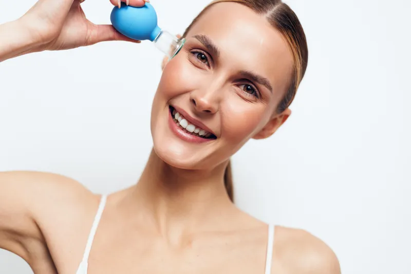 Smiling woman receiving facial treatment, cosmetology technician applies injection near temple, close up on white background, beauty care and self care concept, soft studio lighting
