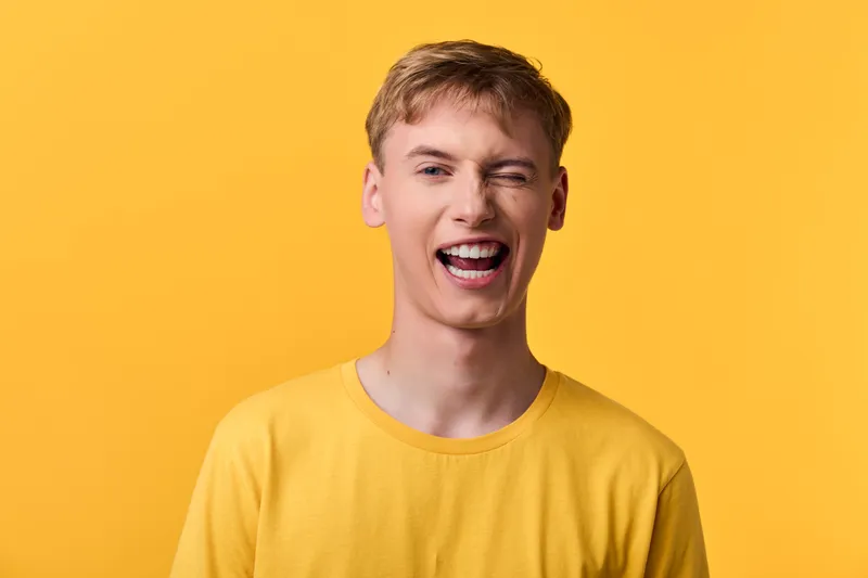 Smiling man in casual yellow shirt against a bright yellow backdrop, studio shot capturing a joyful expression, upbeat mood, headshot style for lifestyle and positivity