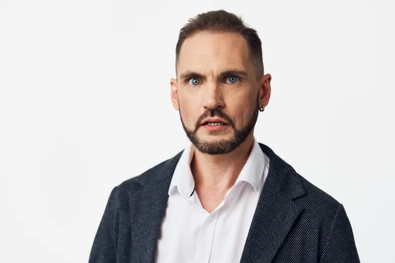 Professional man in business attire with a focused expression, isolated on a colored background, conveying ambition, confidence, and proactive leadership for corporate projects and campaigns.