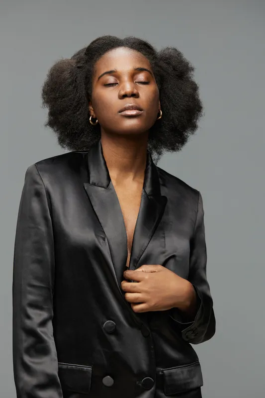 Elegant black woman in a satin blazer, showcasing confidence and serenity, with natural hair, perfect for fashion and empowerment themes