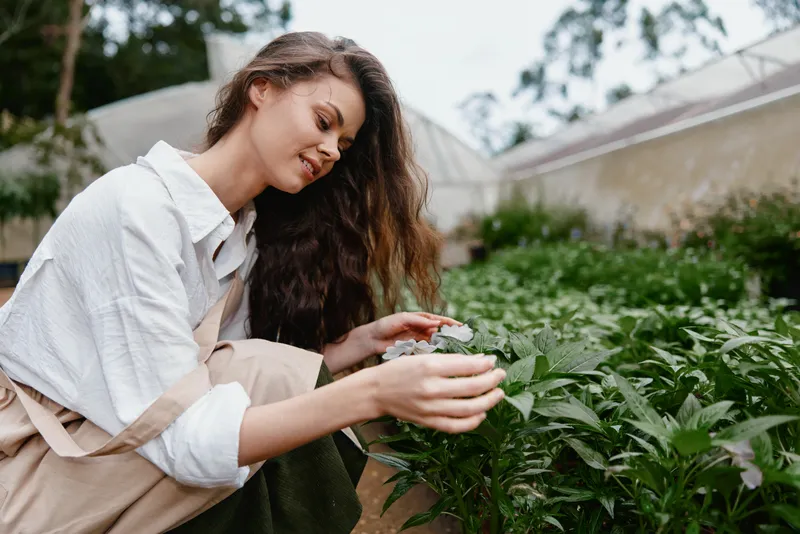 Young woman caring for plants in a serene garden, showcasing a passion for gardening and nature, highlighting sustainable living and connection with greenery