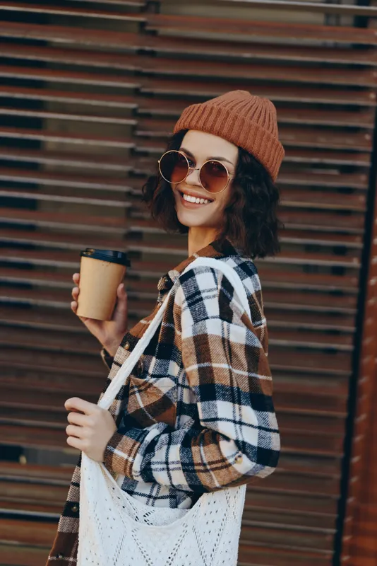 woman coffee smile urban beanie sunglasses tote plaid enjoying golden hour glow, authenticity and candid lifestyle vibe, mindful living portrait with emotional storytelling and cozy autumn fashion