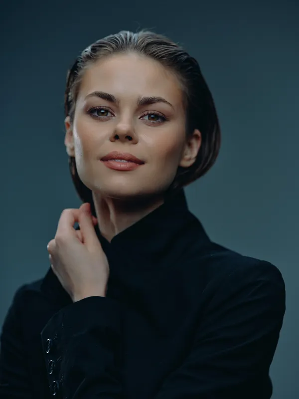confident woman wearing black coat with soft makeup against dark background