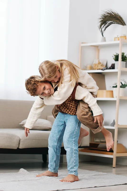 Authentic moment of playful bonding as a caregiver carries a child, capturing a casual lifestyle scene and the warmth of everyday school age joy and resilience.