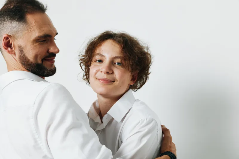 A professional business man expresses warmth and confidence while embracing a colleague against an isolated colored background, conveying teamwork, trust, motivation, and subtle pride in a corporate
