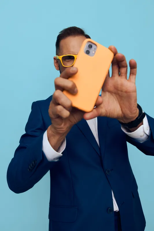A professional man in a suit takes a self portrait on a vibrant blue background, an isolated color scene that conveys confidence, focus, and a light, playful mood.