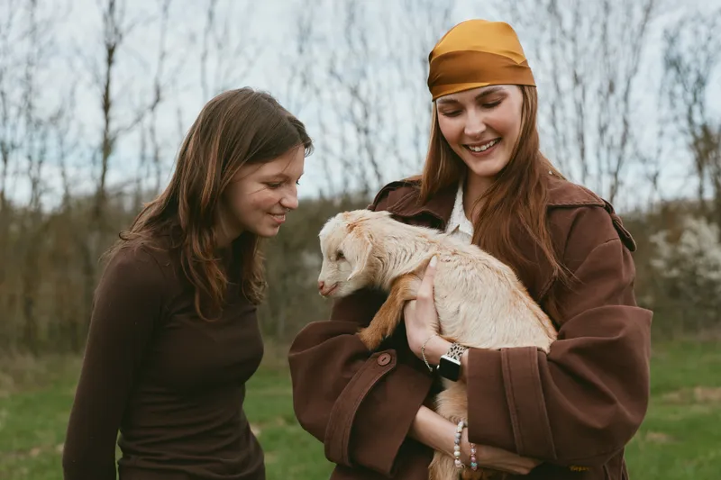 goat kid lifestyle outdoors women farm animal companionship rural friends portrait cheerful natural scenery outdoor field meadow animals care gentle playful sunshine smile tenderness bond humanity