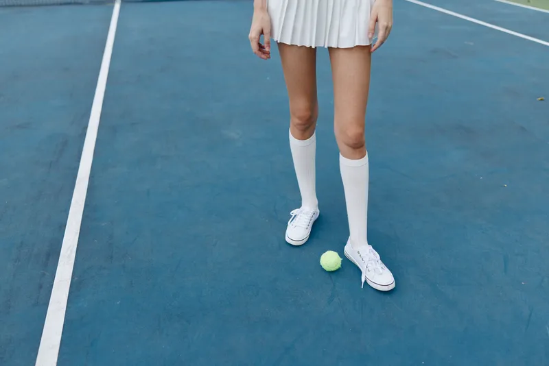 Female tennis player in a sporty outfit on a blue court, showcasing excitement with a yellow tennis ball, perfect for sports and fitness themes