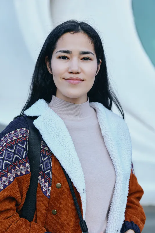 Woman wearing a quilted jacket with shearling lining outdoors, calm expression, casual streetwear style, urban backdrop, soft natural light, fashion and everyday lifestyle