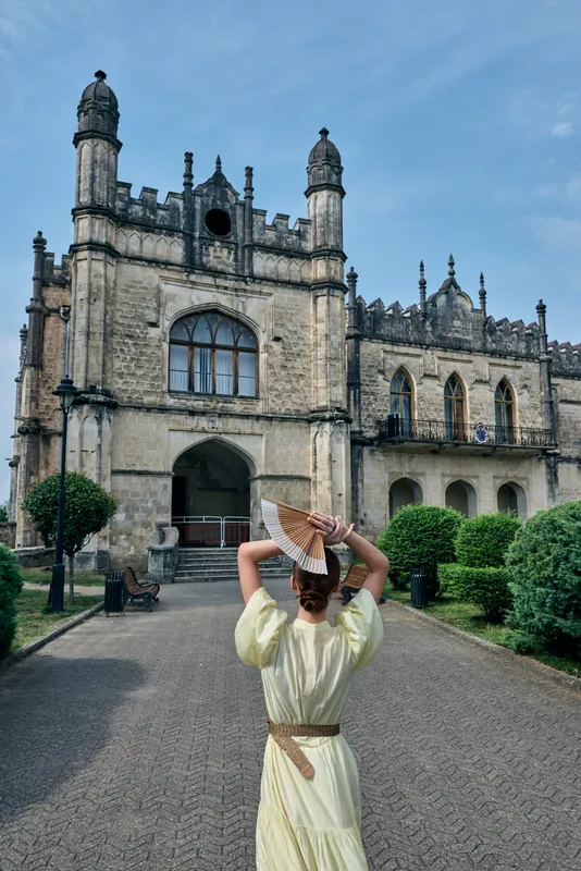 Woman vintage dress approaching historic mansion with ornate architecture, travel highlighting authenticity inclusivity