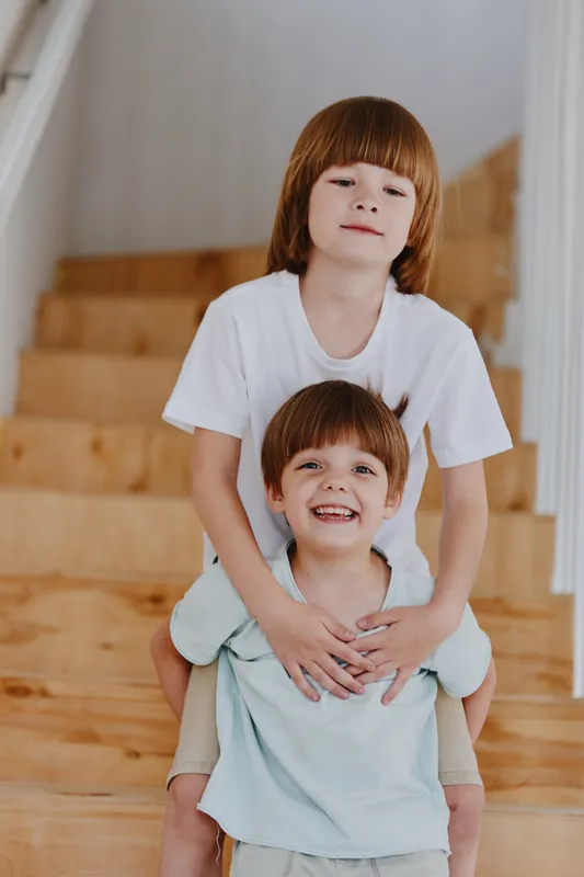 Joyful children playing together on wooden stairs, showcasing a warm and playful atmosphere with bright smiles and casual clothing.