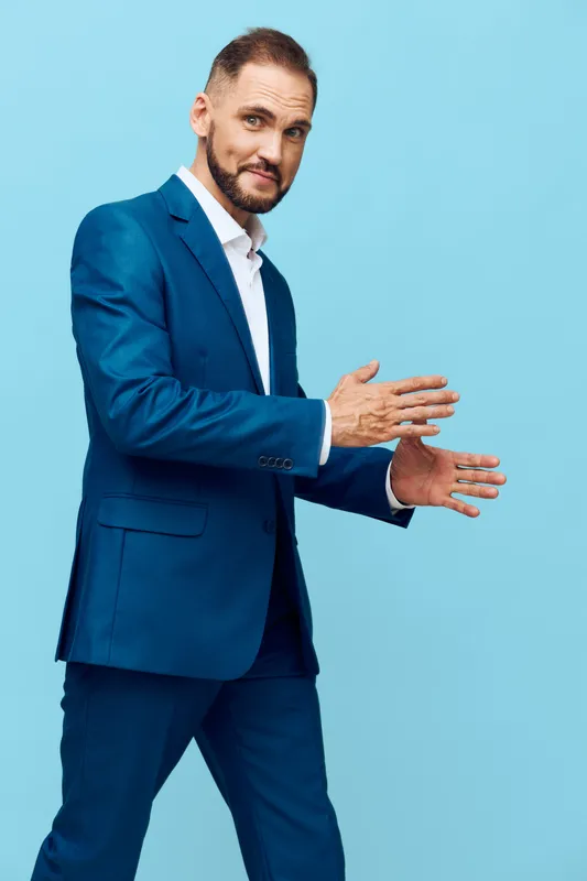 A professional man in a blue suit stands against a solid colored background, expressing confidence and focus in a modern business scene.