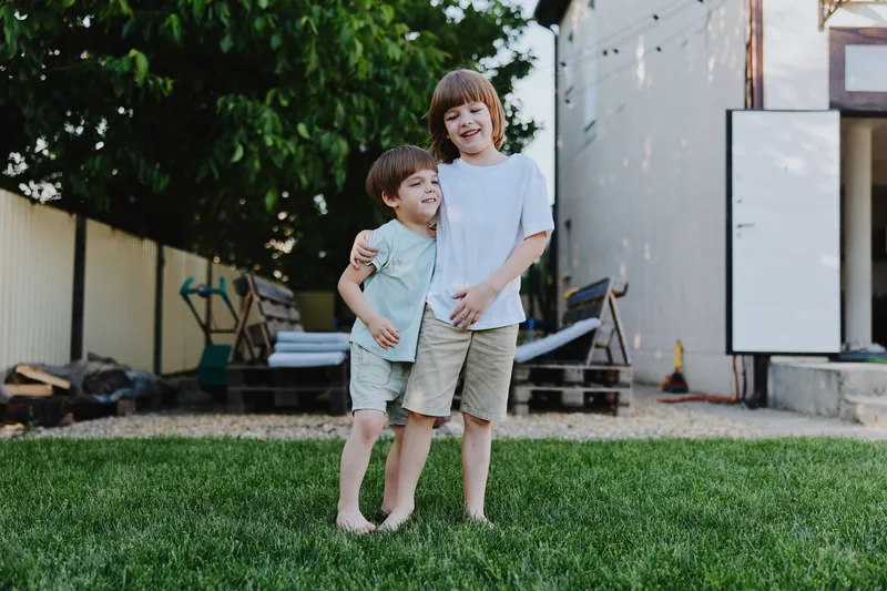 Joyful boys playing together in a backyard, showcasing friendship and happiness. Their laughter reflects the carefree spirit of childhood in a sunny environment.