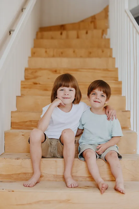 Happy boys sitting on wooden stairs, enjoying their time together, capturing the essence of childhood friendship and playful moments in a cozy environment.