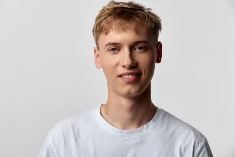 Young man white t shirt smile studio casual headshot with a friendly vibe in a bright setting, ideal for fashion, lifestyle and modern branding campaigns