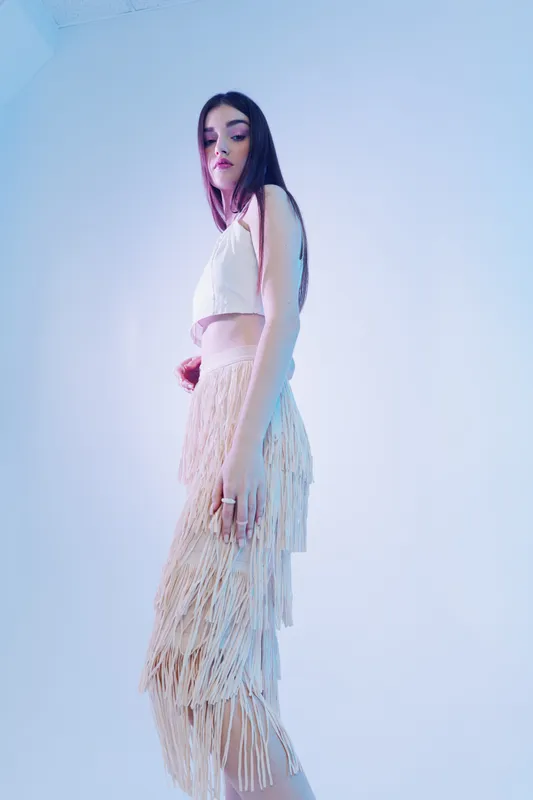 Young woman in stylish fashion outfit poses in studio with soft lighting. Concept of beauty, fashion, elegance, and modern style for creative projects.