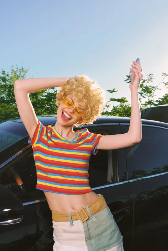 woman lifestyle retro vintage fashion sunny outdoor car colorful joyful bright playful summer hairstyle sunglasses striped top denim belt smile candid portrait