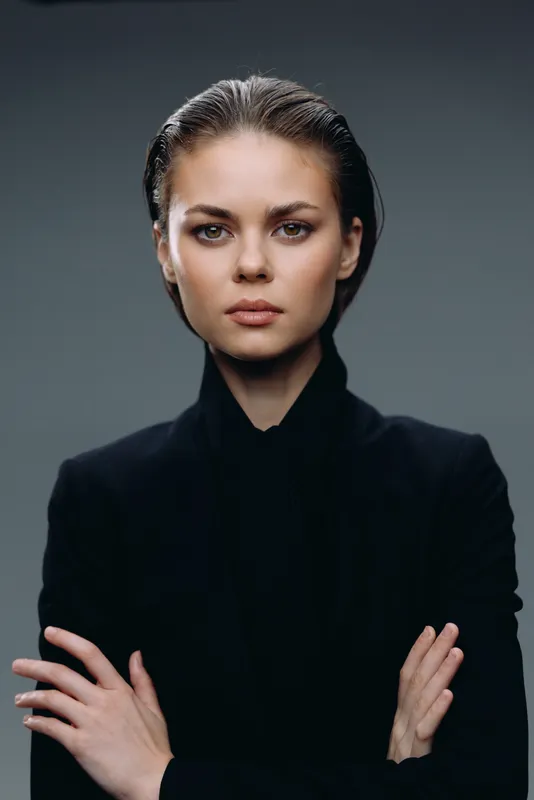 Serious woman in black clothes with crossed arms and confident expression