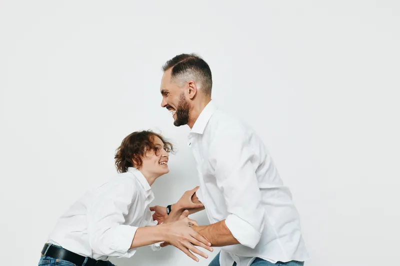 A professional businessman shares a warm moment with a colleague, exuding confidence and ambition against an isolated white background. The scene conveys leadership, approachability, and teamwork in