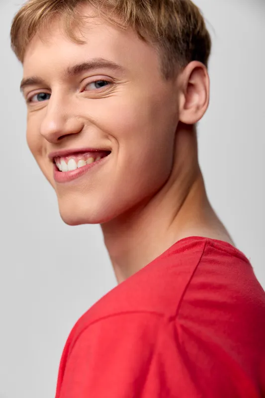 Smiling man in a red shirt, close up shot emphasizing a warm expression, casual style and confident vibe for lifestyle, positivity, and branding imagery