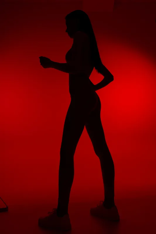 Silhouette of a woman sport fitness figure with athletic posture, dark lighting, and red background creating a striking, dynamic mood for health and exercise themes.
