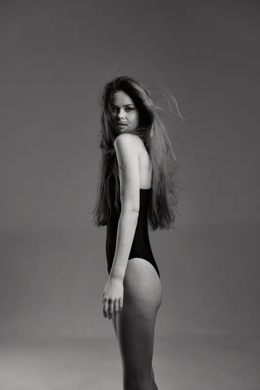 Black and white portrait of a young woman in a swimsuit with long hair and serious expression