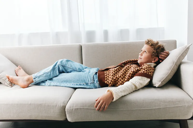Authenticity shines as a student relaxes on a cozy sofa, capturing a lifestyle moment of simple play and study after class in a quiet home setting with natural light and soft textures.