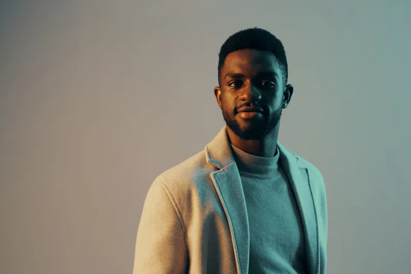 Stylish African man in elegant attire, conveying confidence against a cool toned background, perfect for concepts of fashion and modern masculinity
