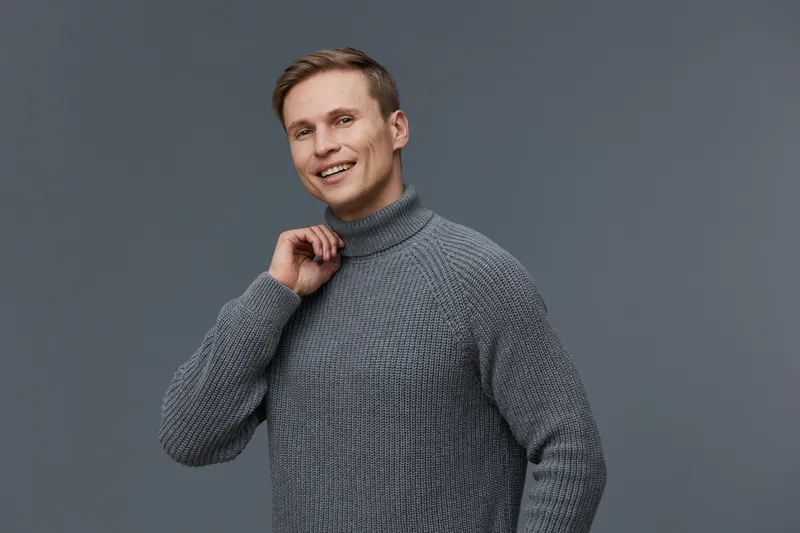smiling man in gray turtleneck sweater touch neck look camera isolated on gray background digital detox mental health concept