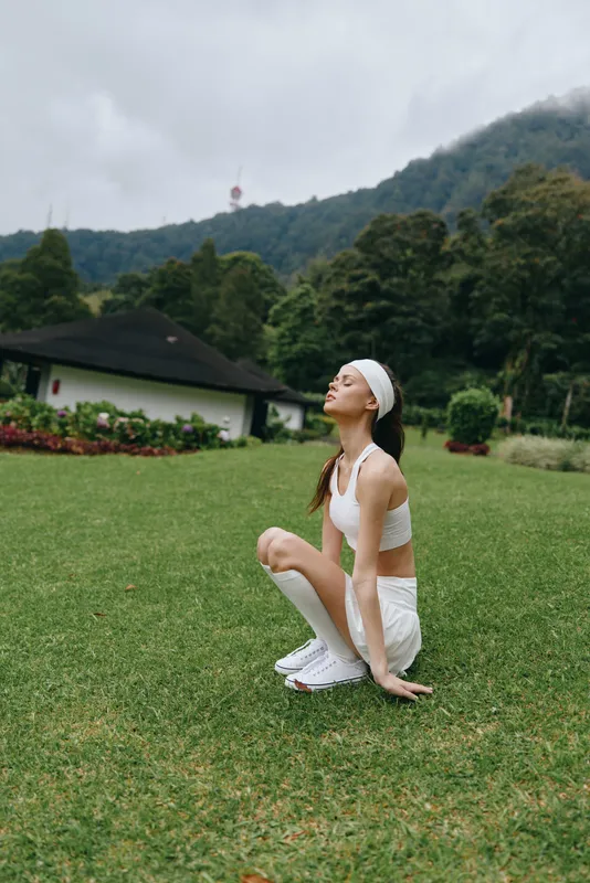 Young athletic woman practicing yoga outdoors in nature, wearing comfortable fitness clothing, showcasing balance and mindfulness in a serene environment
