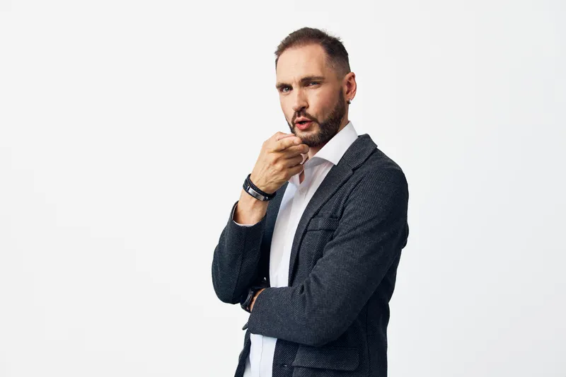 Male business professional with calm confidence and thoughtful emotion, set against an isolated colored background. Studio portrait showing a poised, attentive gesture and strong presence.