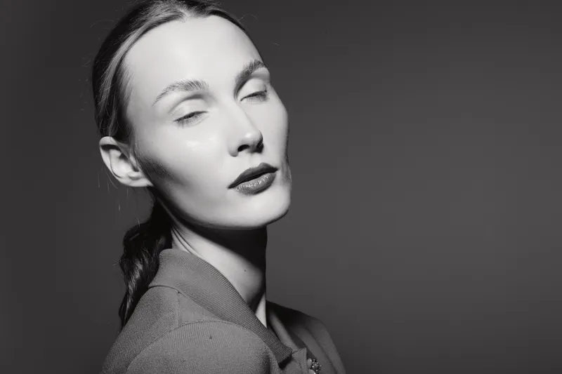 Portrait of a fair skinned white woman with closed eyes in monochrome lighting, wearing a jacket. Concept of elegance, beauty, and calmness.