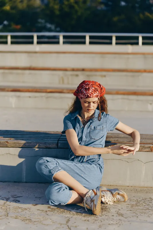 lifestyle woman in modern boho-western denim street style sitting relaxed outdoors with natural light and warm film color tones