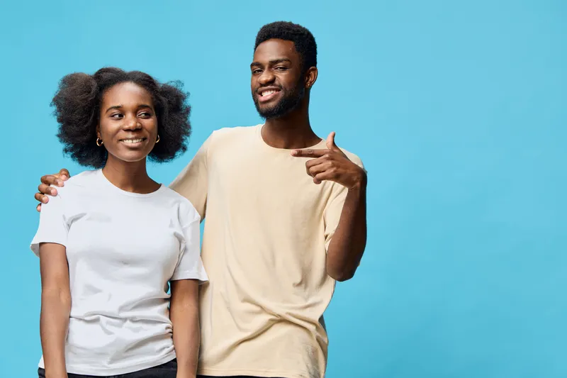 Happy diverse young couple posing together against a bright blue background, showcasing playful emotions and casual fashion suitable for modern lifestyle imagery
